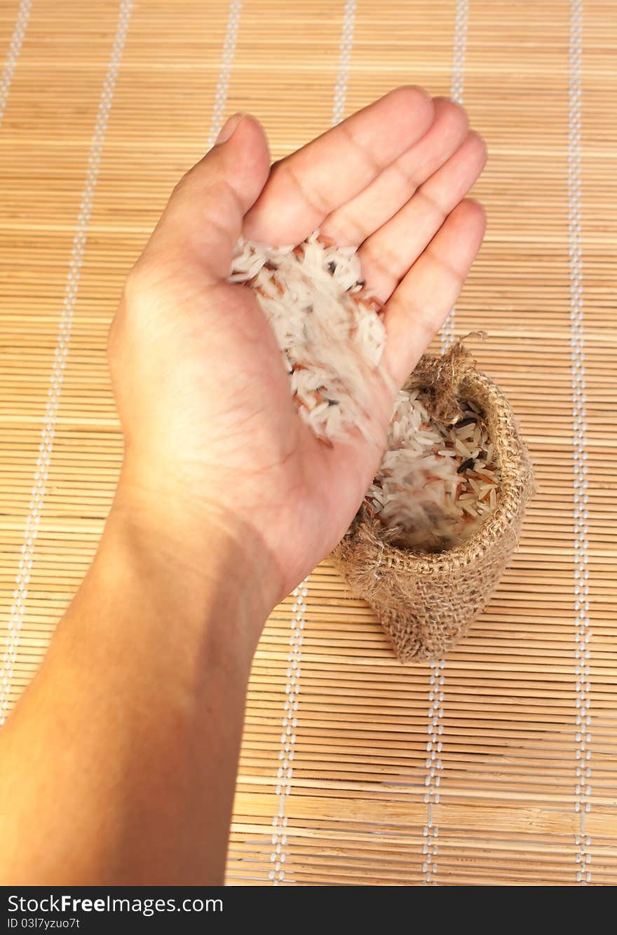 Hand pouring raw rice to woven bag for food concept