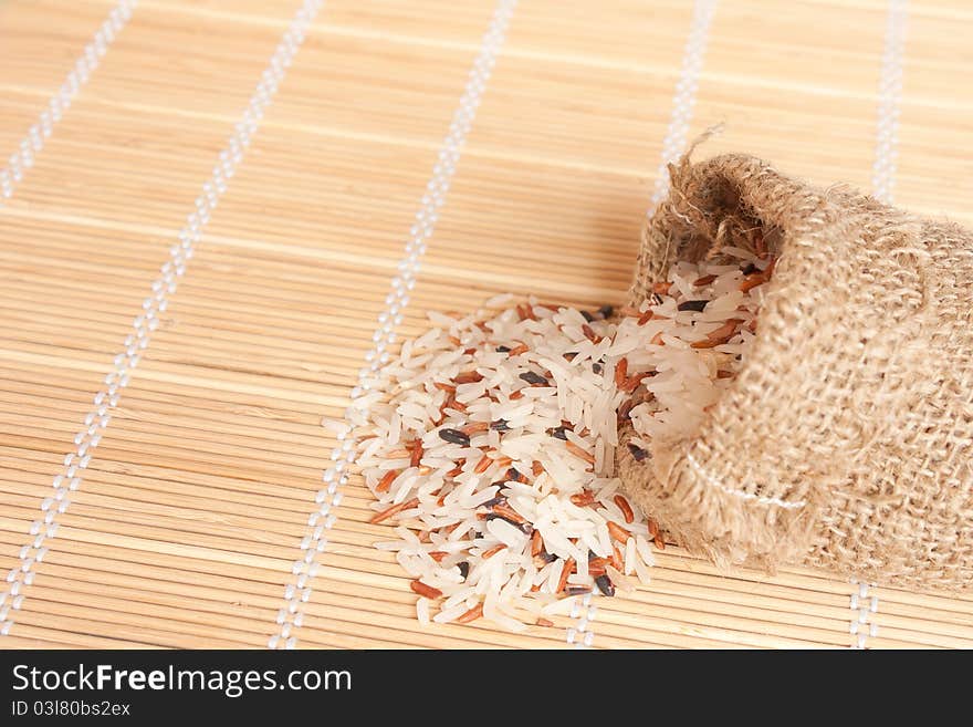 Raw rice pouring frim woven bag from bamboo pad