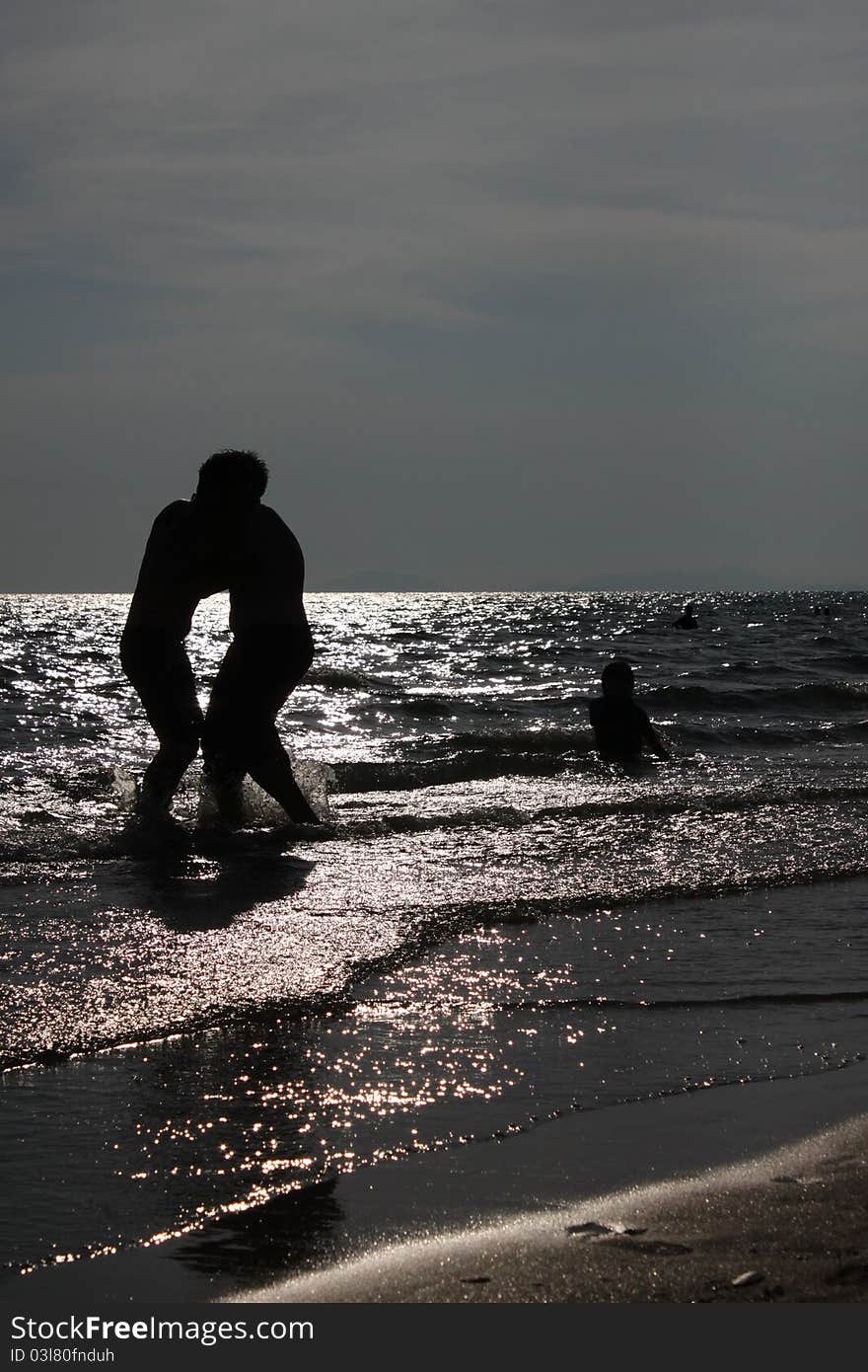 Two boys are playing on the beach at sunset. Two boys are playing on the beach at sunset