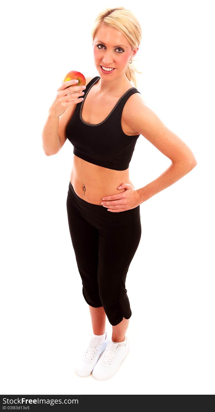 A young female dressed in black exercise clothes eating an apple