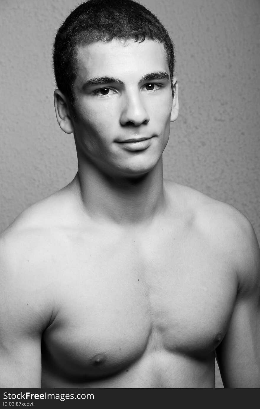 Half body portrait of muscular young man, black and white studio background.