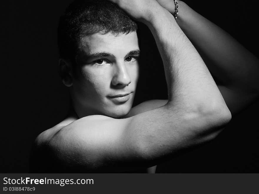 Portrait of muscular young man, black and white studio background.