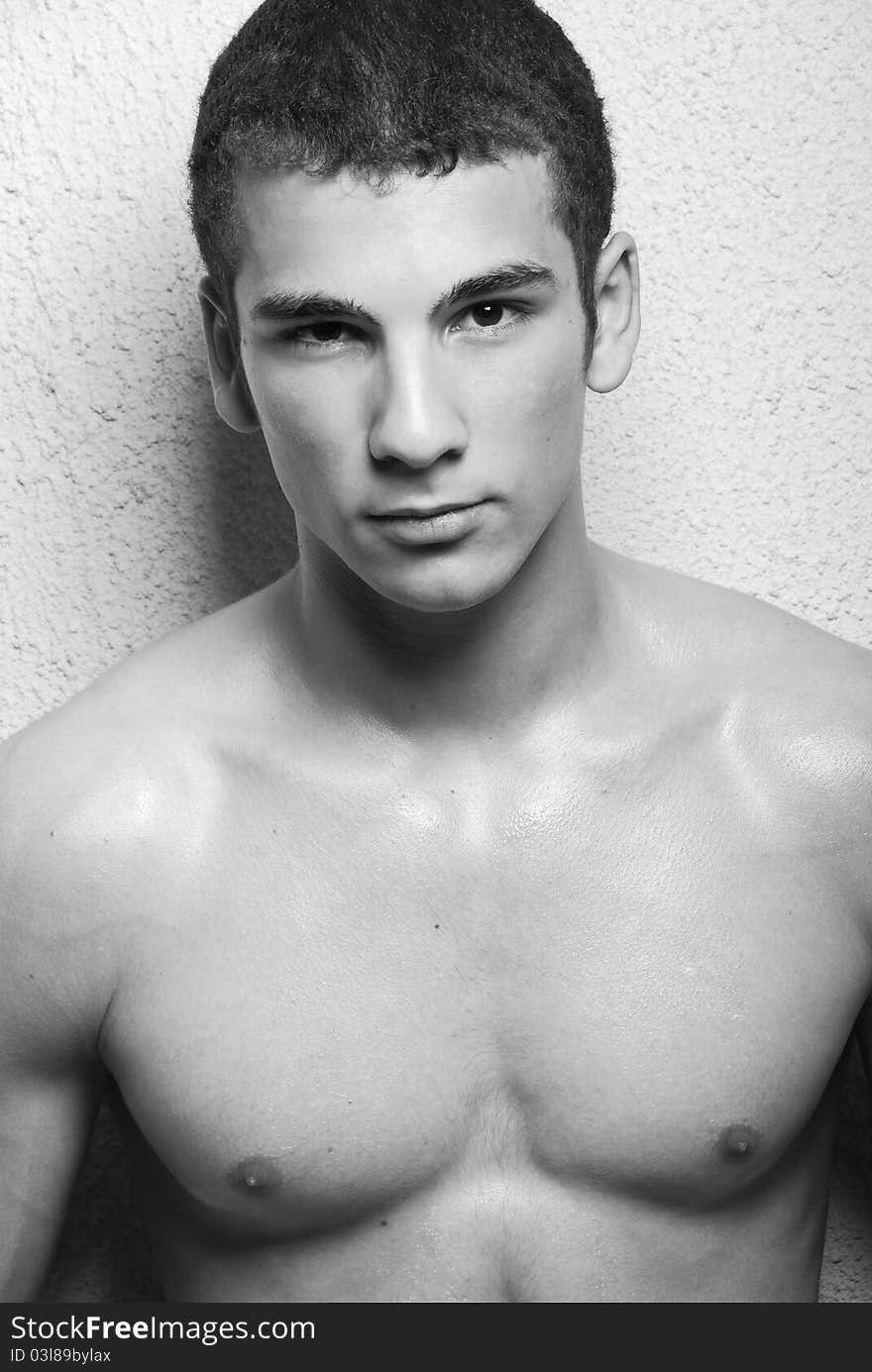 Half body portrait of muscular young man, black and white studio background.