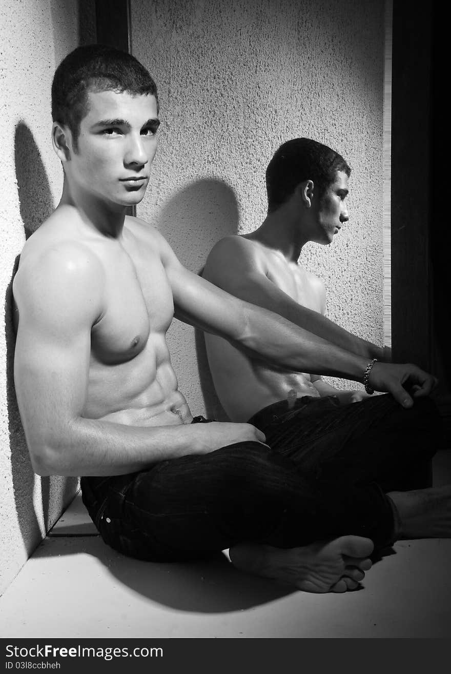 Black and white half body portrait of muscular young man reflected in full length mirror. Black and white half body portrait of muscular young man reflected in full length mirror.