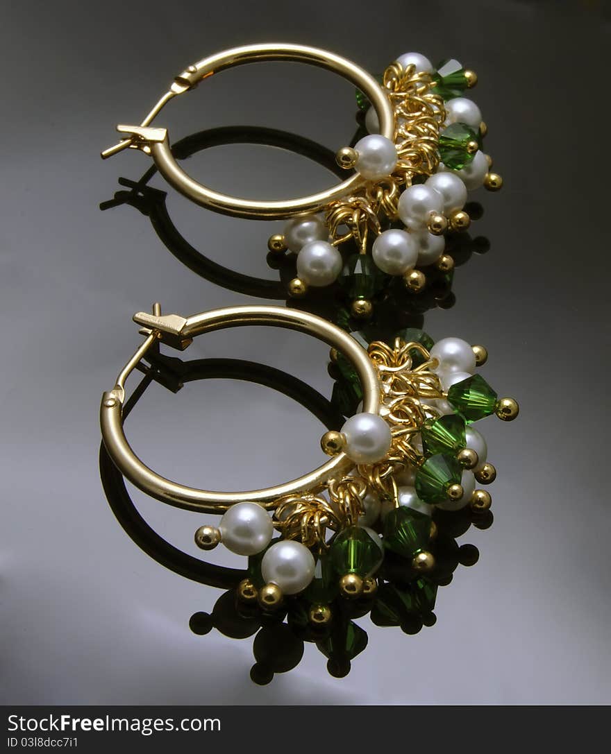 Close up of handmade earrings with gemstones over black background