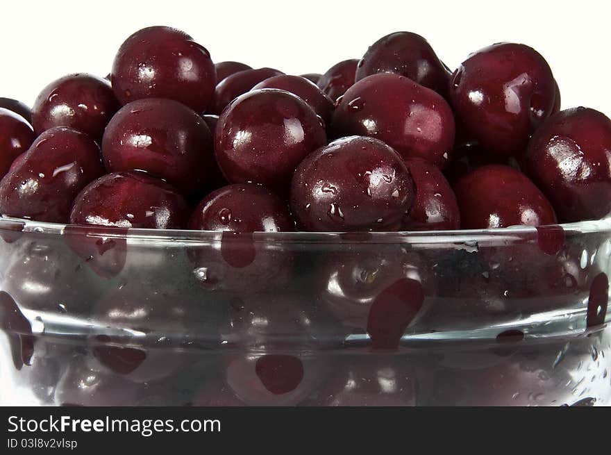 Red sweet cherries in glass plate on a white background