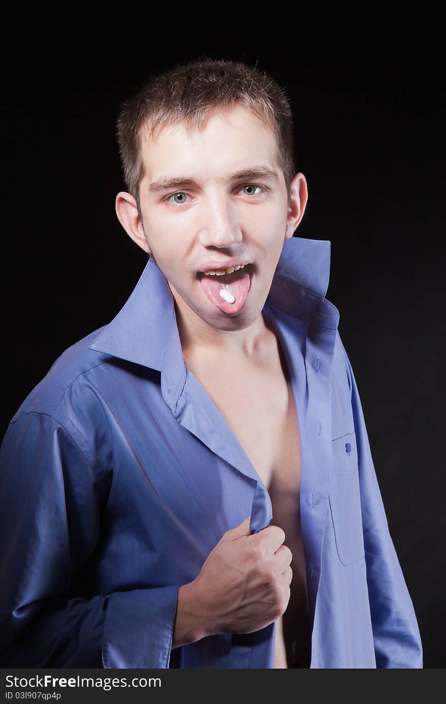 Portrait of young handsome man taking a pill in studio