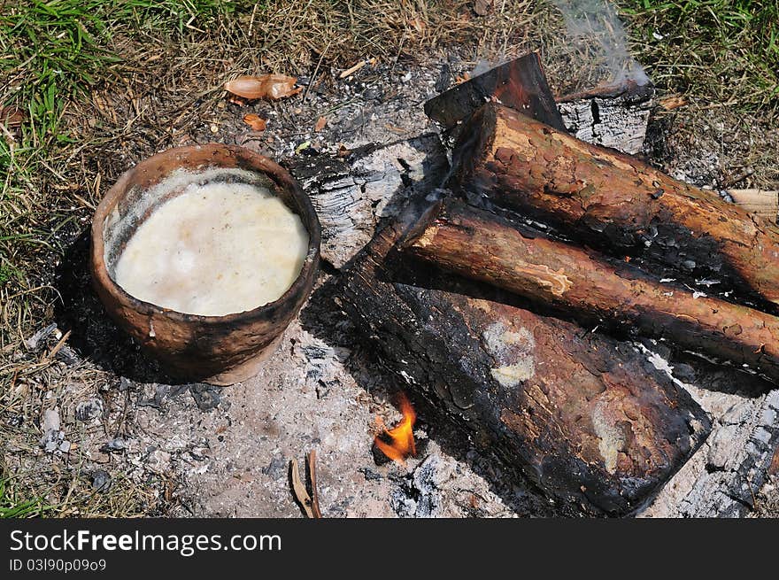 Soup in ceramics pot and firewood