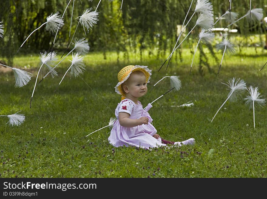 1 year old baby sitting in meadow with flying dandelion seeds. 1 year old baby sitting in meadow with flying dandelion seeds