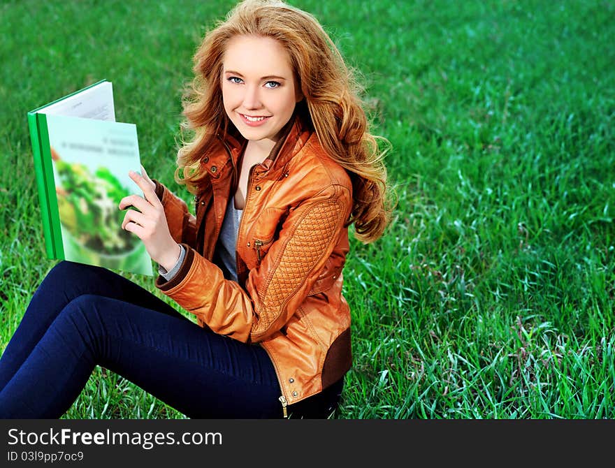 Beautiful smiling young woman reading a book outdoors. Beautiful smiling young woman reading a book outdoors.