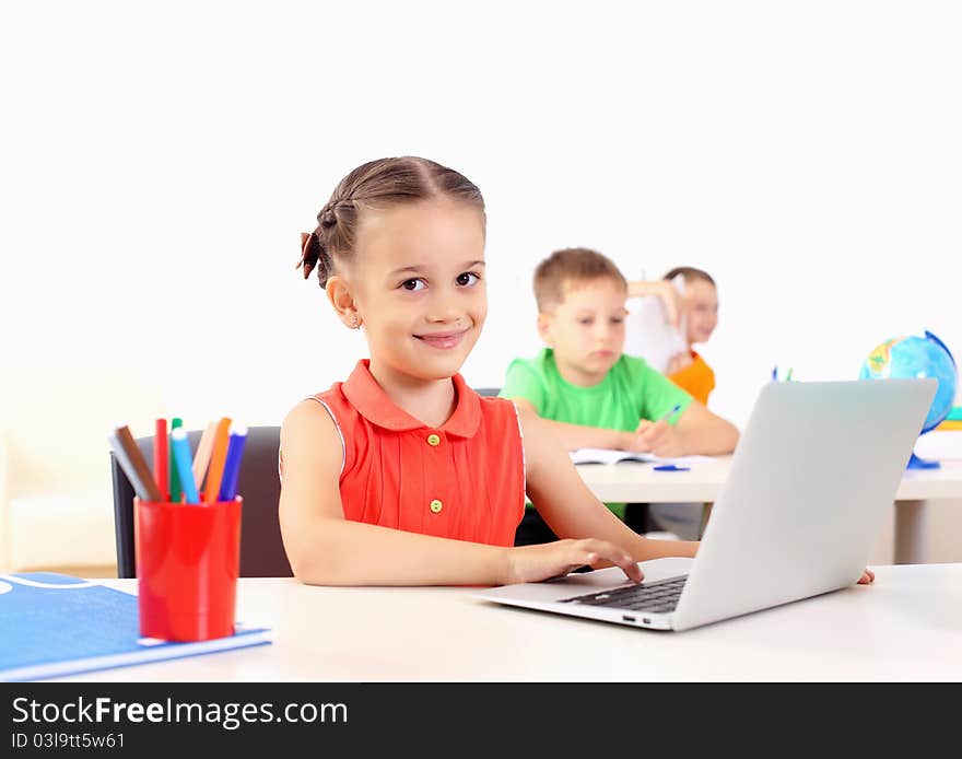 Portrait of a young girl working on laptop at school at the desk.