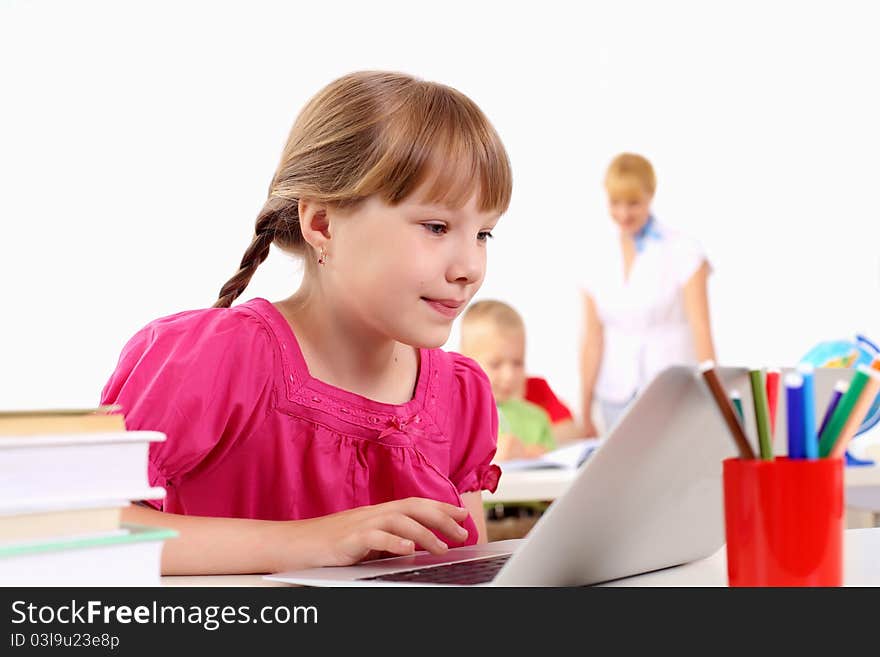 Portrait of a young girl working on laptop at school at the desk.