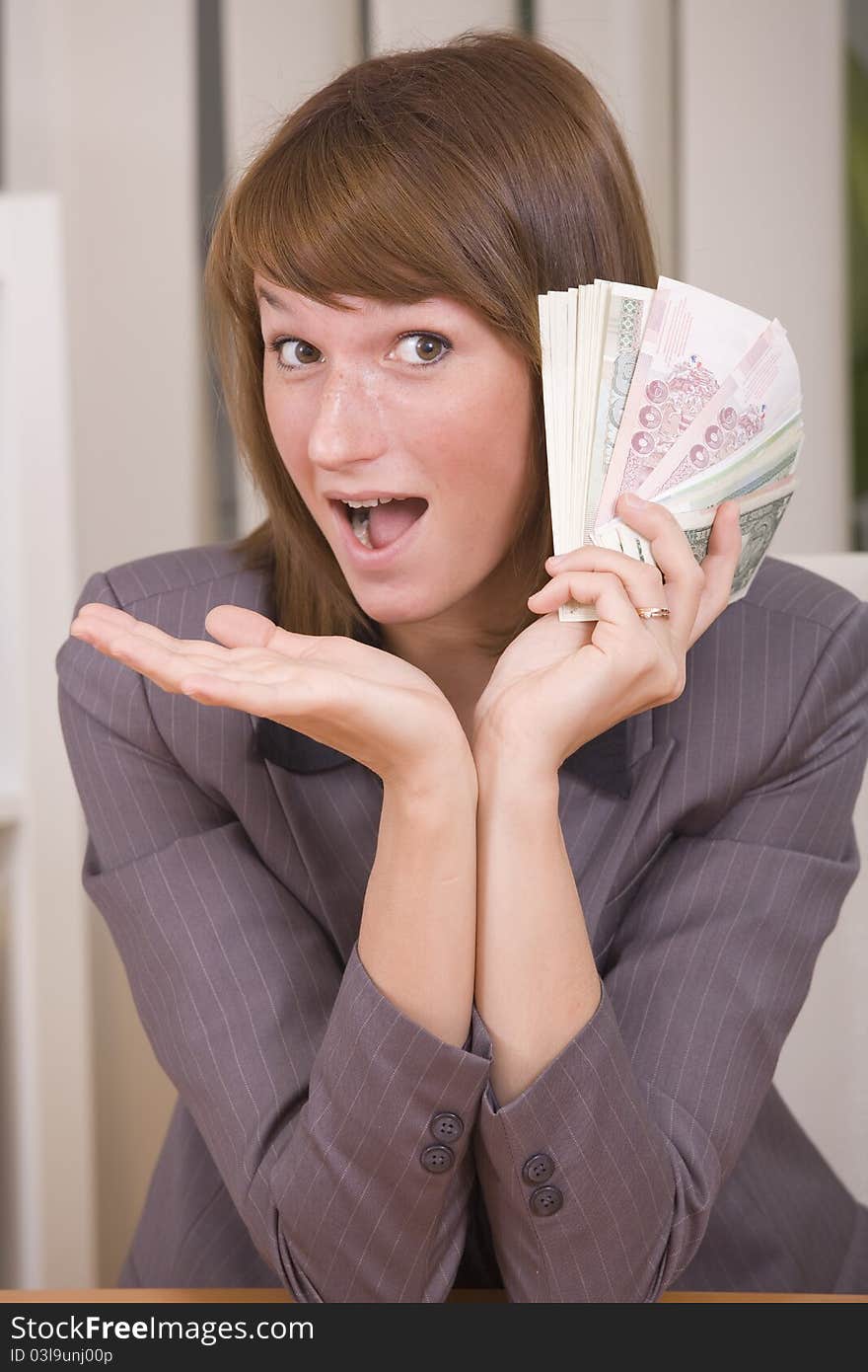 Happy business woman with stack of money in office