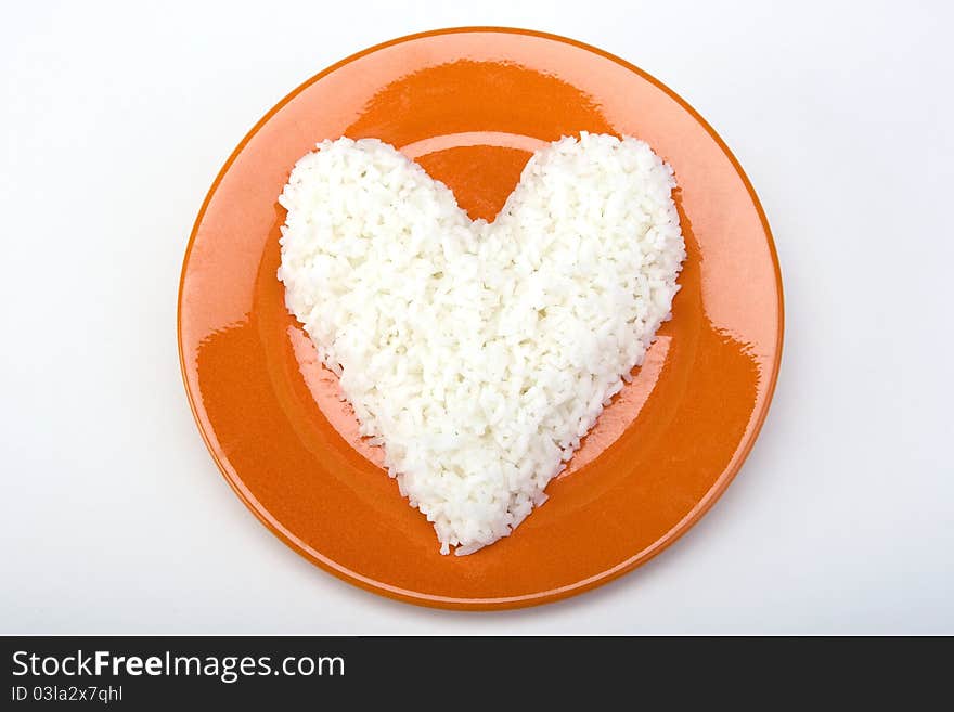 Heart shaped white rice on an orange ceramic plate. Heart shaped white rice on an orange ceramic plate