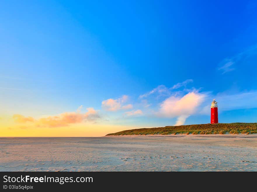 Seaside With Sand Dunes And Lighthouse At Sunset