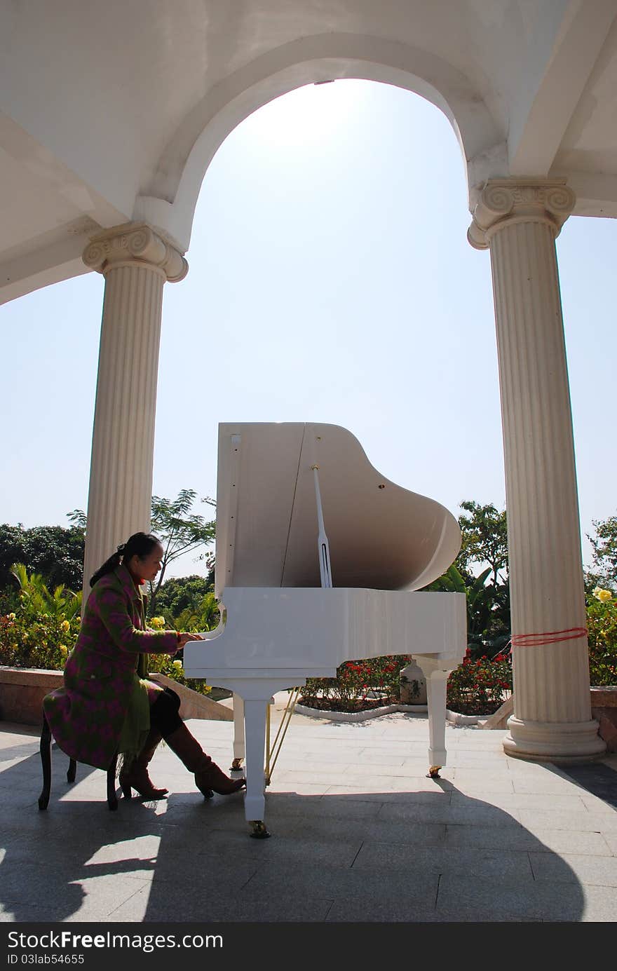 A woman playing piano in the arched corridor.