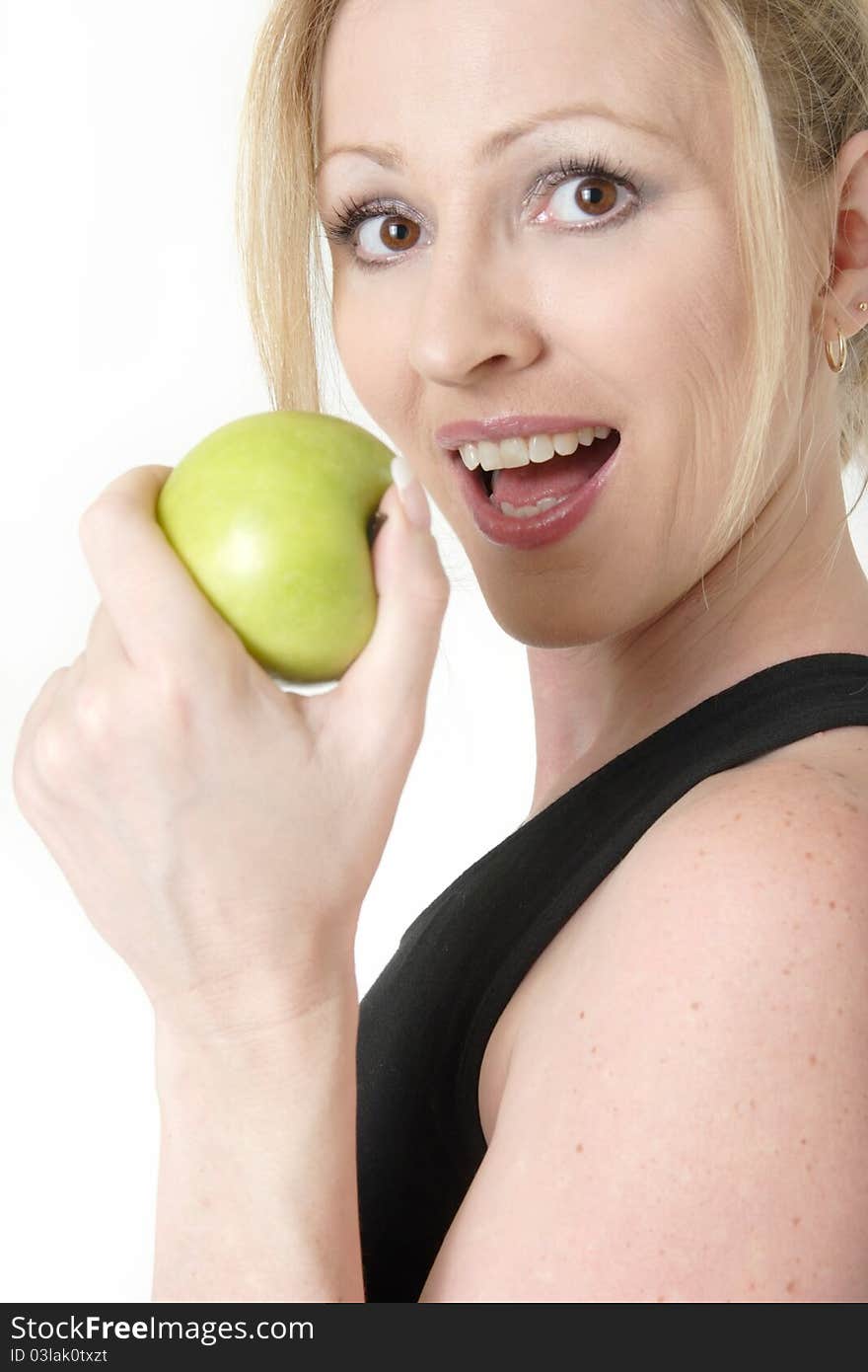 Attractive blond caucasian woman holding a green apple near mouth ready to take a bite. Attractive blond caucasian woman holding a green apple near mouth ready to take a bite