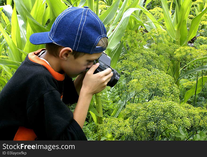 The boy with a camera is keen on shooting on the nature. The boy with a camera is keen on shooting on the nature.