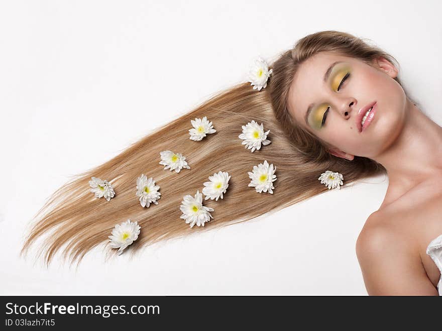 Attractive young woman lying on white background covered with flowers. Attractive young woman lying on white background covered with flowers