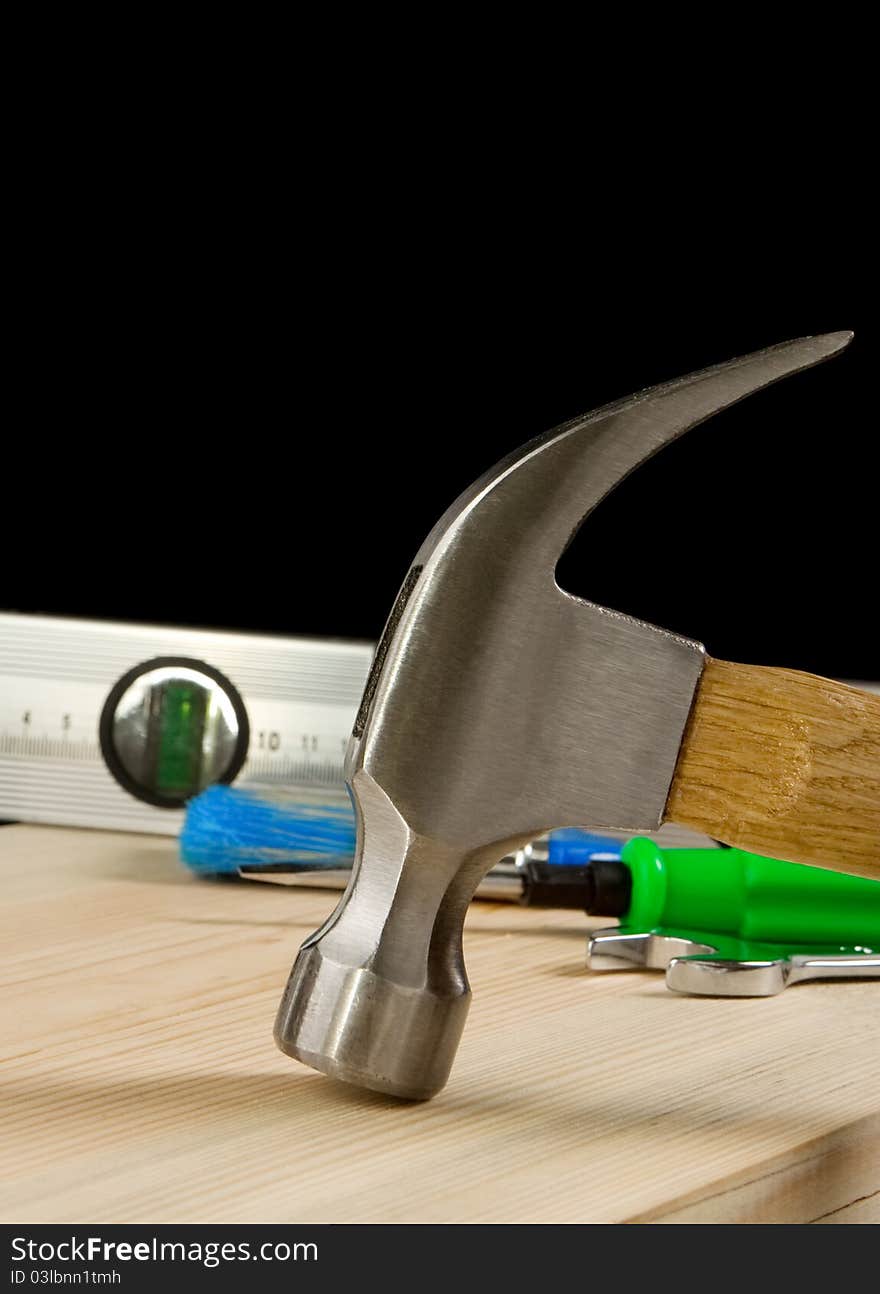 Hammer and other tool at wooden brick isolated on black background. Hammer and other tool at wooden brick isolated on black background