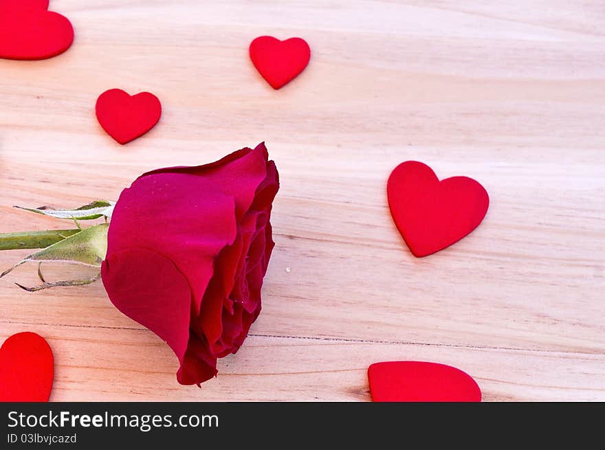 Red rose with hearts in wood background