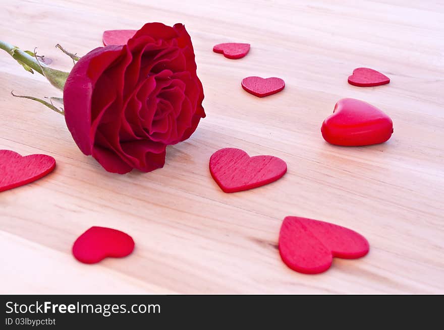 Red rose with hearts in wood background