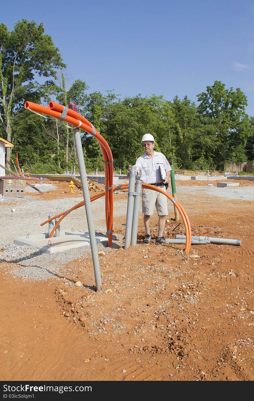 Building inspector checking new electrical & plumbing pipes coming into new residential community. Building inspector checking new electrical & plumbing pipes coming into new residential community