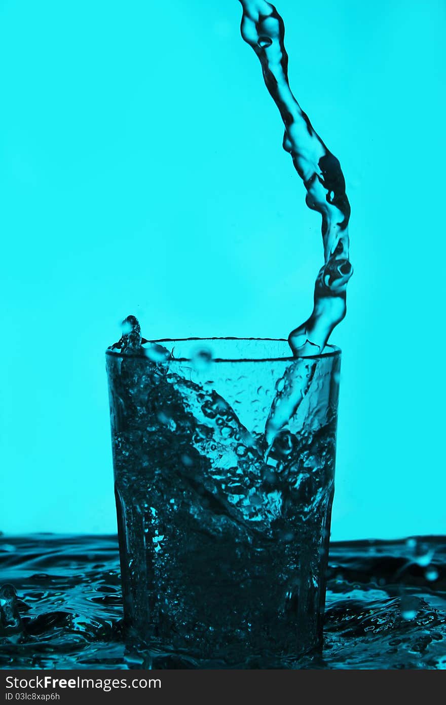 Liquid pouring into the glass over blue background