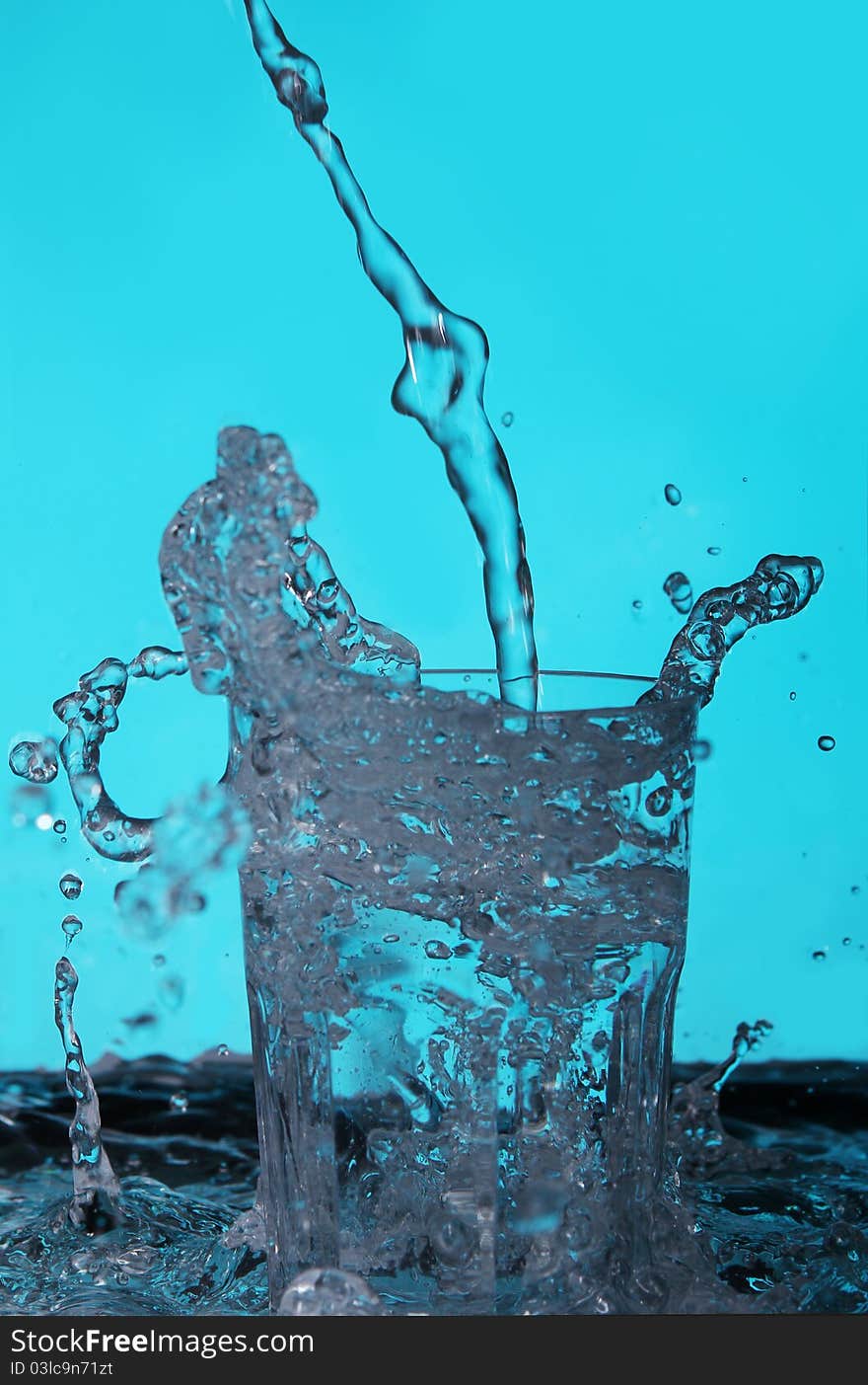 Liquid pouring into the glass over blue background