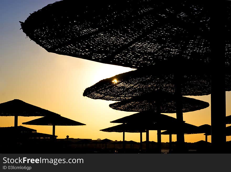 Silhouettes of beach's umbrellas at the sunset