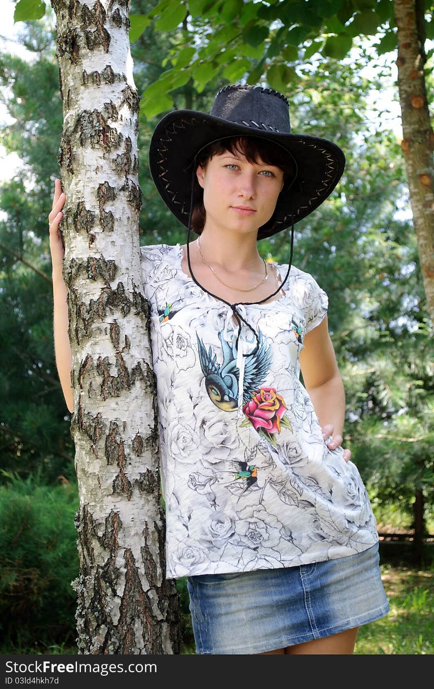 Beautiful girl in the hat around birch