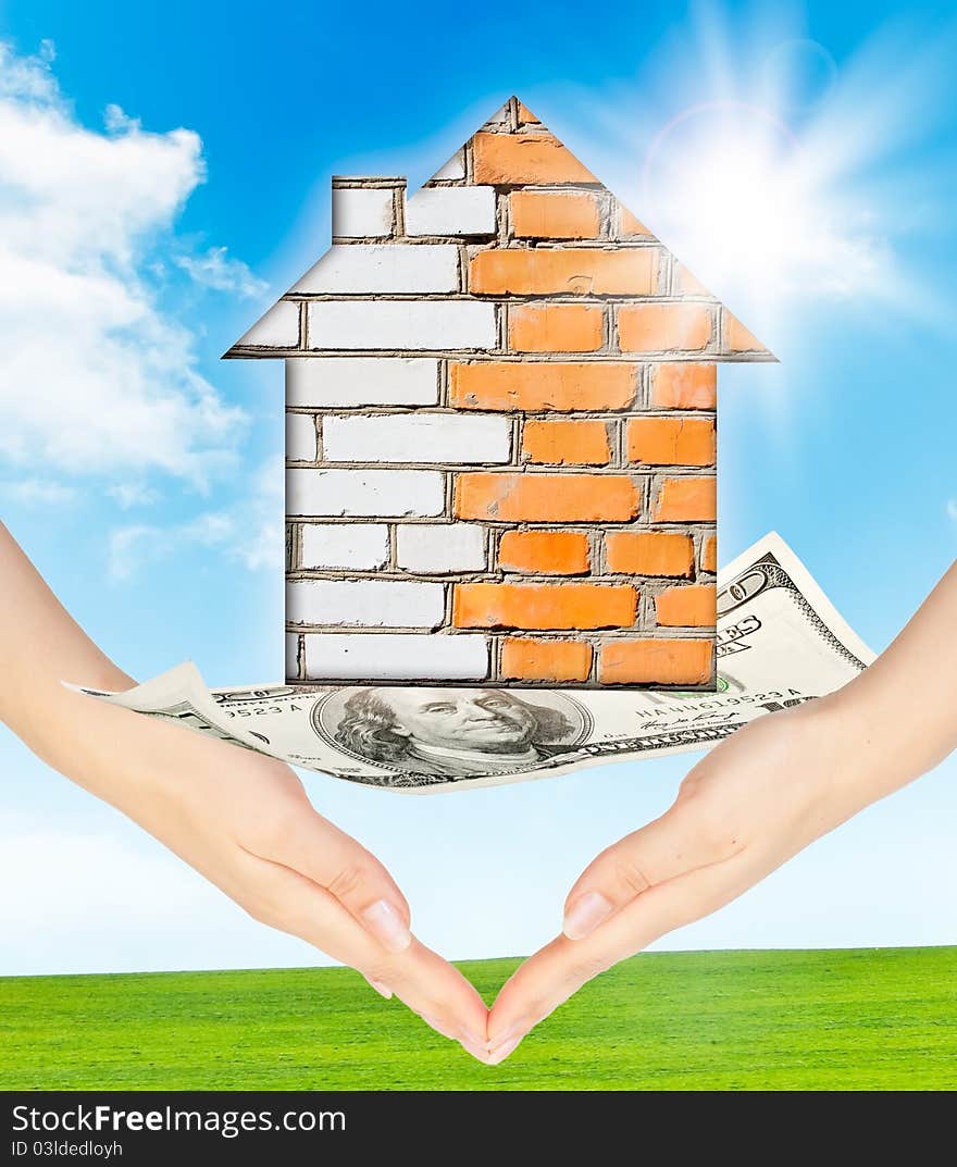 Hands holding model of a brick house on nature background