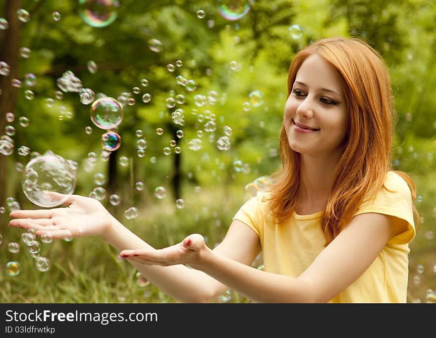 Girl in the park under soap bubble rain.