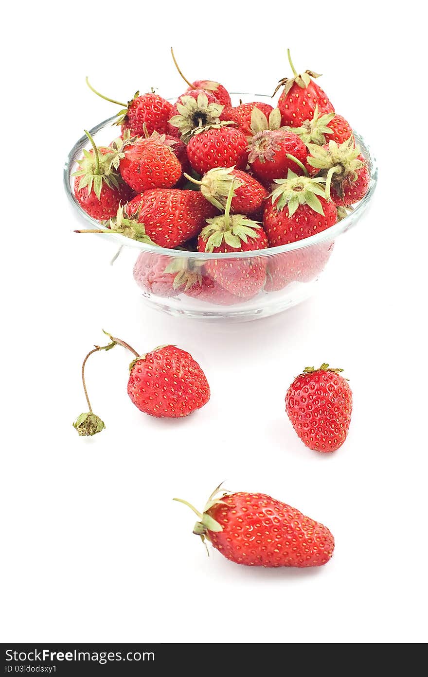 Glass cup with a strawberry scattered on a white background. Glass cup with a strawberry scattered on a white background