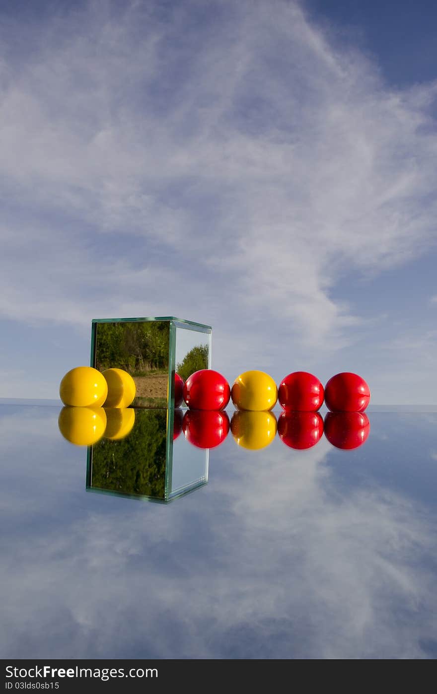 Red and yellow balls on mirror and sky