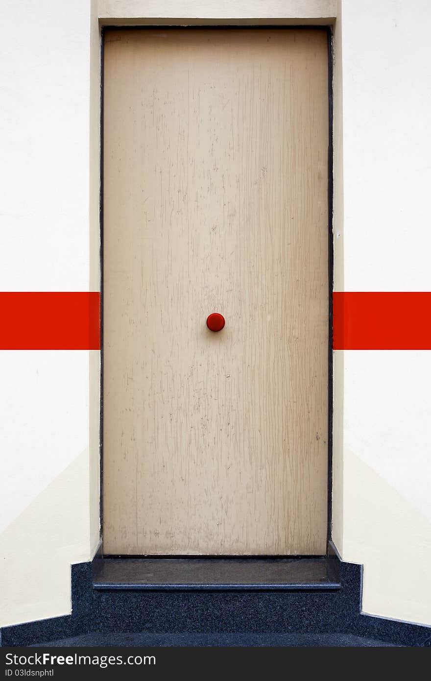 A wood door with a red knob. A wood door with a red knob