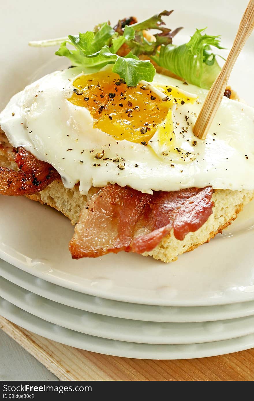 Fried egg and bacon on toasted bread with mixed greens