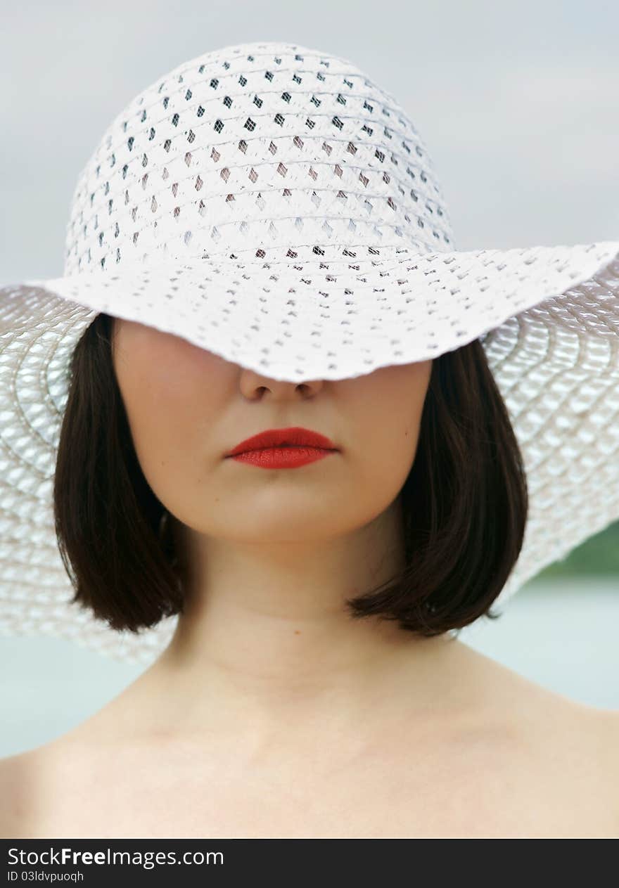 The girl on a beach in a white hat.