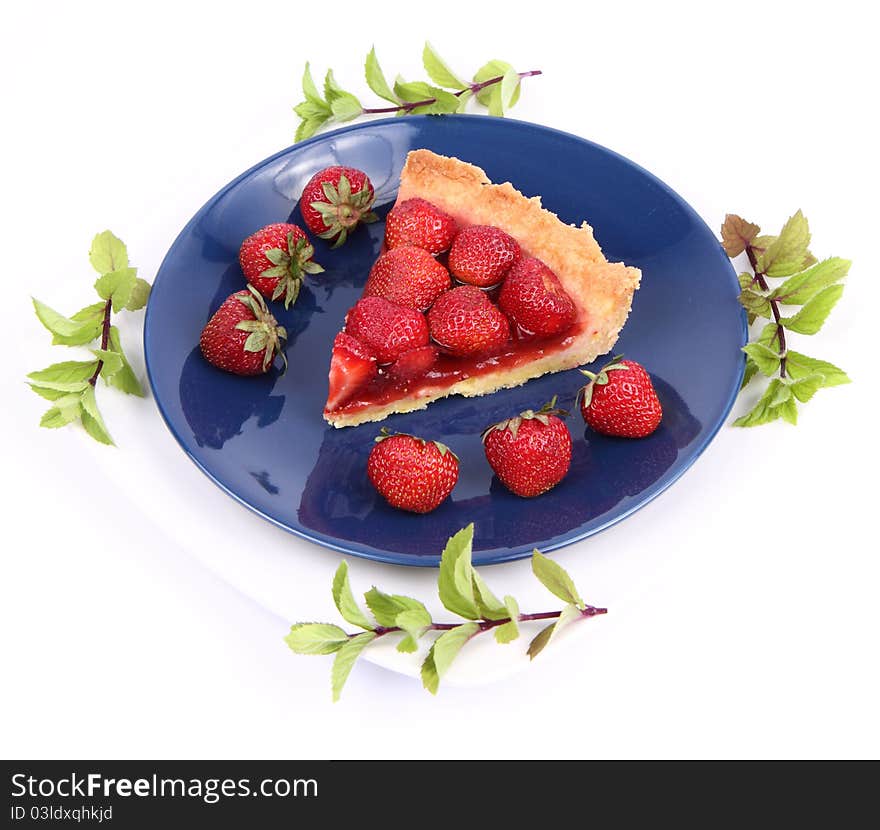 Piece of Strawberry Tart on white plate decorated with strawberries and mint twigs