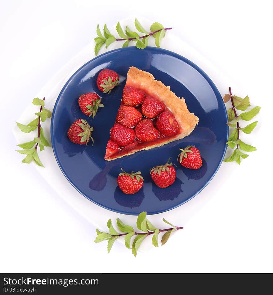 Piece of Strawberry Tart on white plate decorated with strawberries and mint twigs