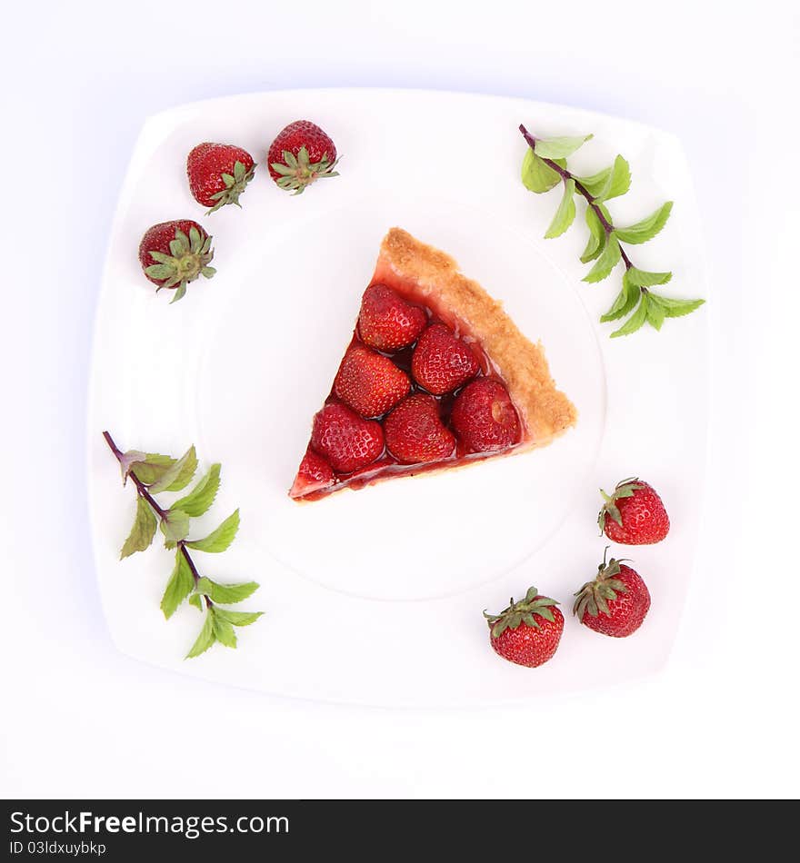 Piece of Strawberry Tart on white plate decorated with strawberries and mint twigs