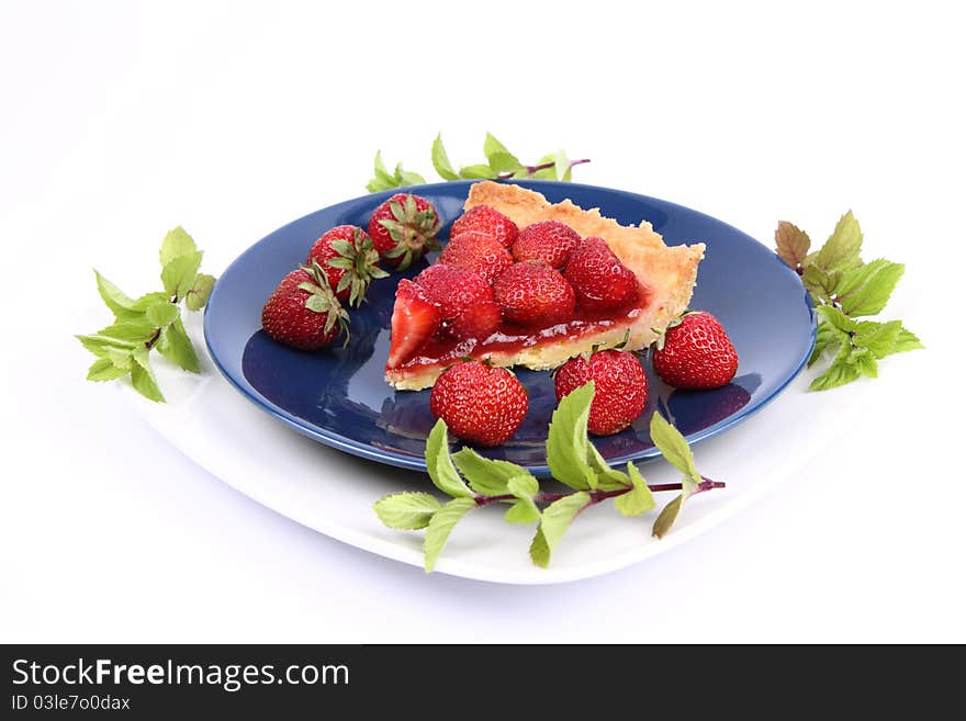 Piece of Strawberry Tart on white plate decorated with strawberries and mint twigs