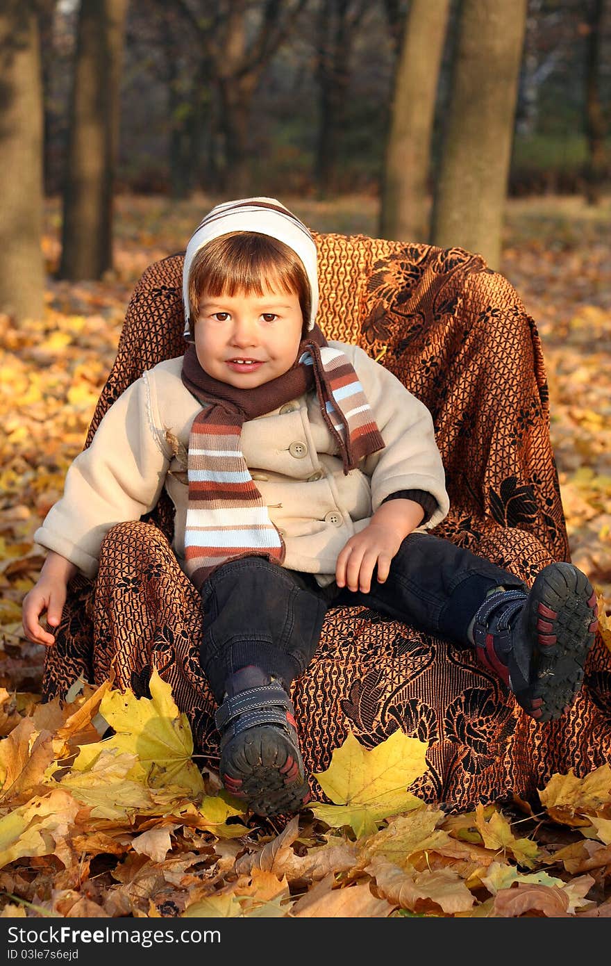 Little Boy Sitting In Chair Outdoors