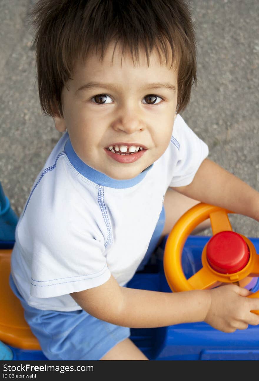 Smiling little boy drives toy car. Smiling little boy drives toy car