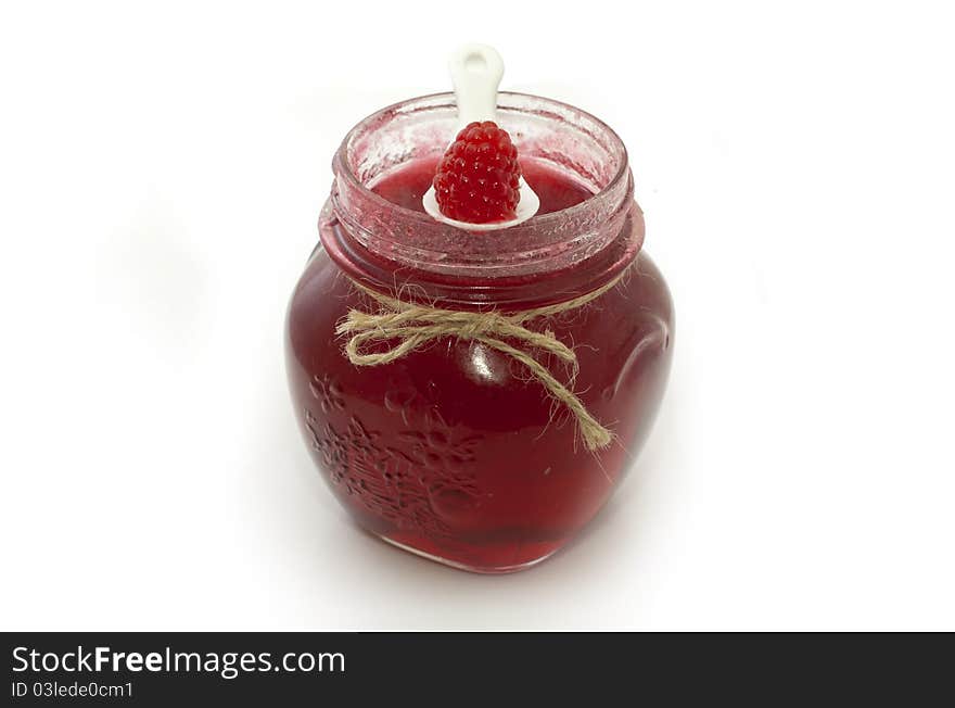 Raspberry jam in glass pot over white