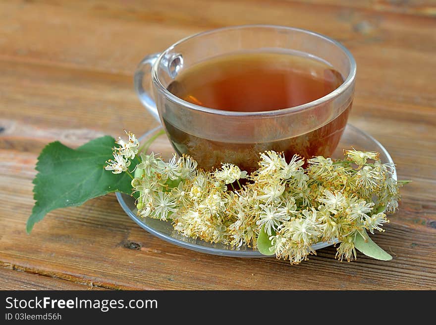 Linden tea on a wooden table. Tea with linden flowers. Cup of tea on the table. Brewed lime beverage. Medicinal tea.