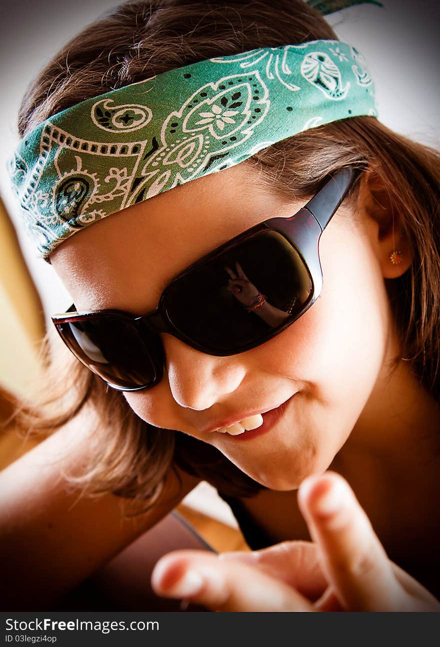 Young girl making the peace sign, reflected in her sunglasses.