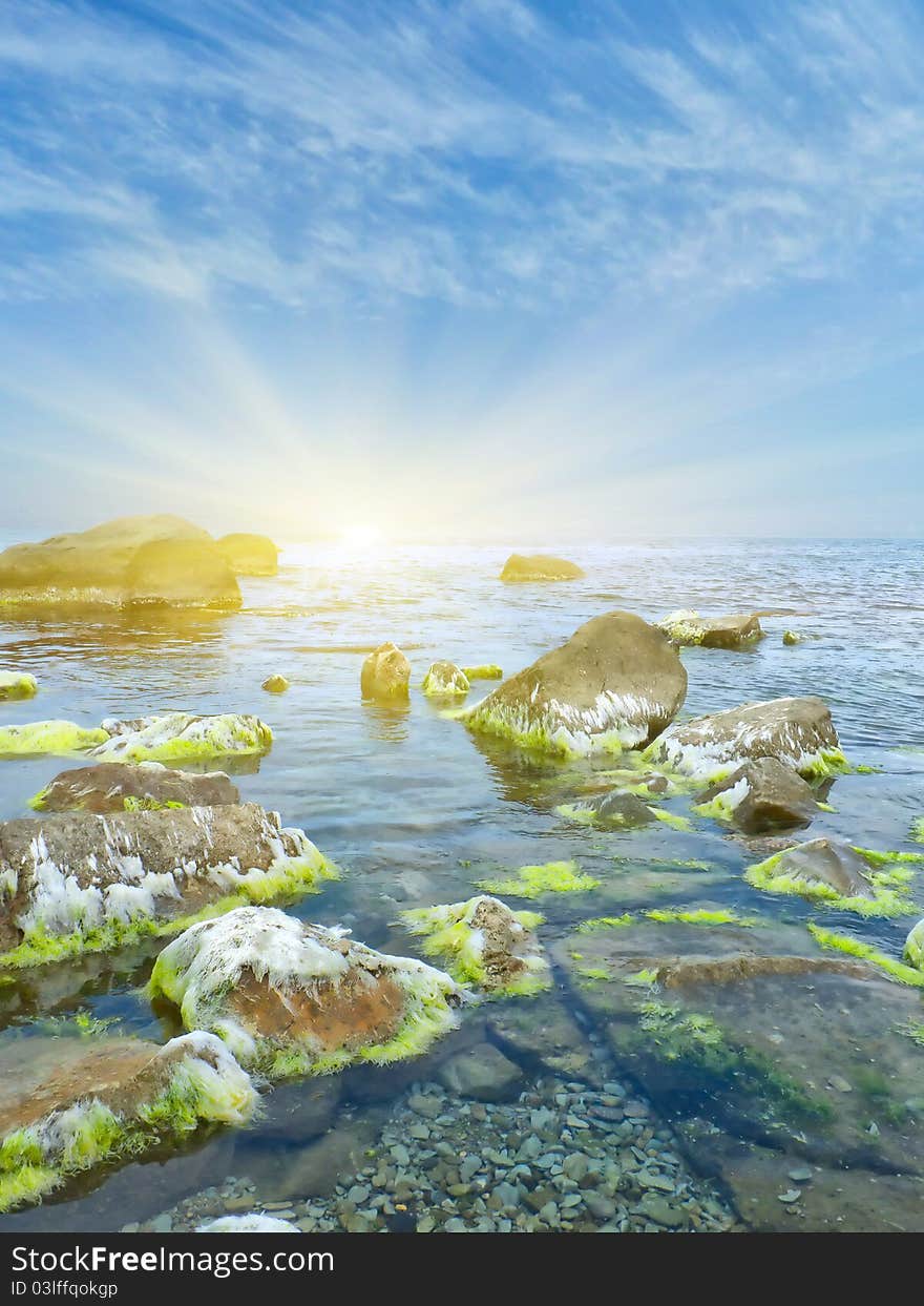 Stones into the sea on sunny sky background