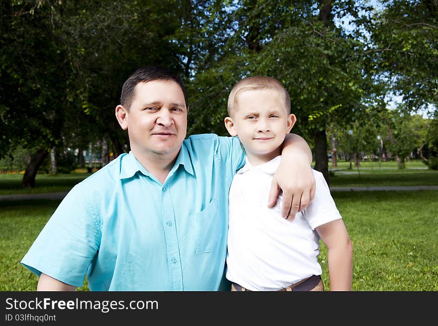 The portrait of the father and the son, stay in park together, are happy. The portrait of the father and the son, stay in park together, are happy