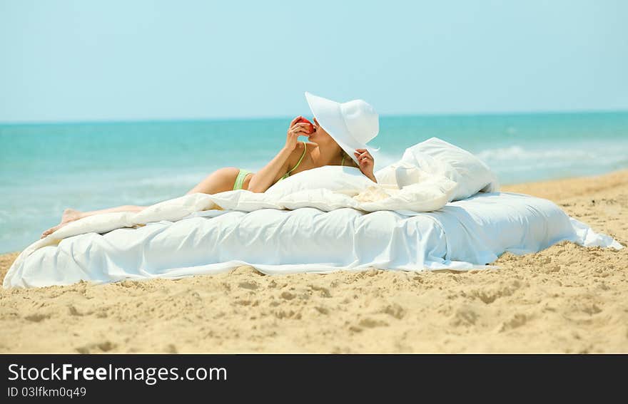 Young beautiful woman eatting a sweet apple in bed on the beach. Young beautiful woman eatting a sweet apple in bed on the beach